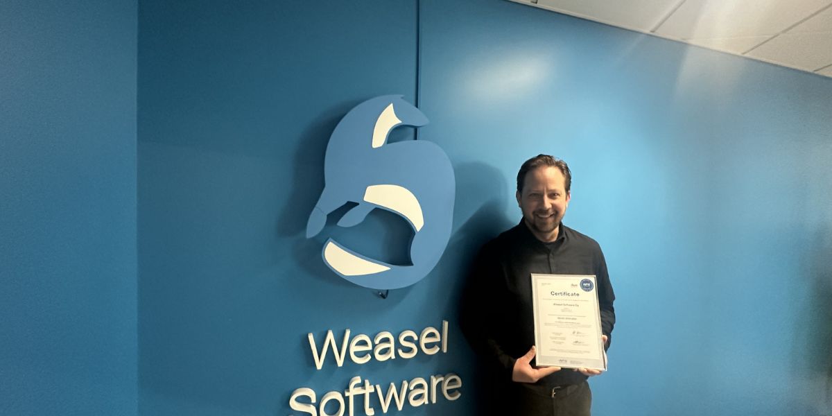 Jussi Suutala pitelee ISO 27001-sertifikaattia Weasel Softwaren toimitiloissa.